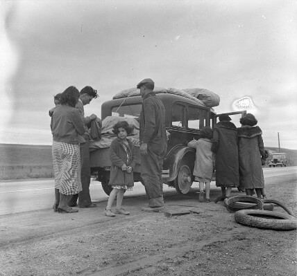 Dorothea Lange, “Migrants, family of Mexicans, on road with tire trouble. Looking for work in the peas.” (1936)